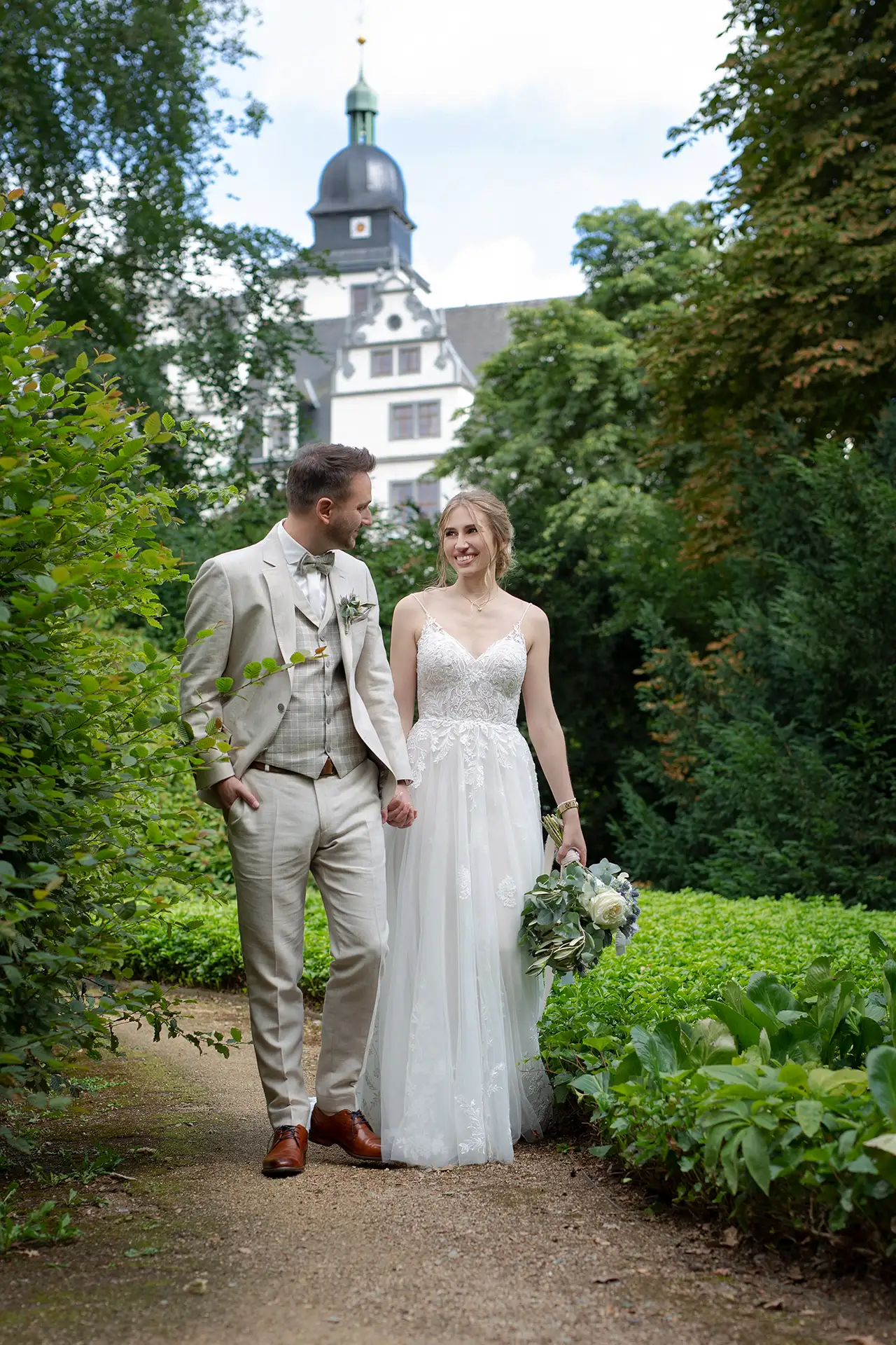 Hochzeitsfotos Wolfsburg - Ein Brautpaar vor einem Schloss mit Brautstrauß